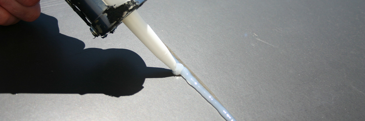 A worker applies a roofing adhesive by Garland.